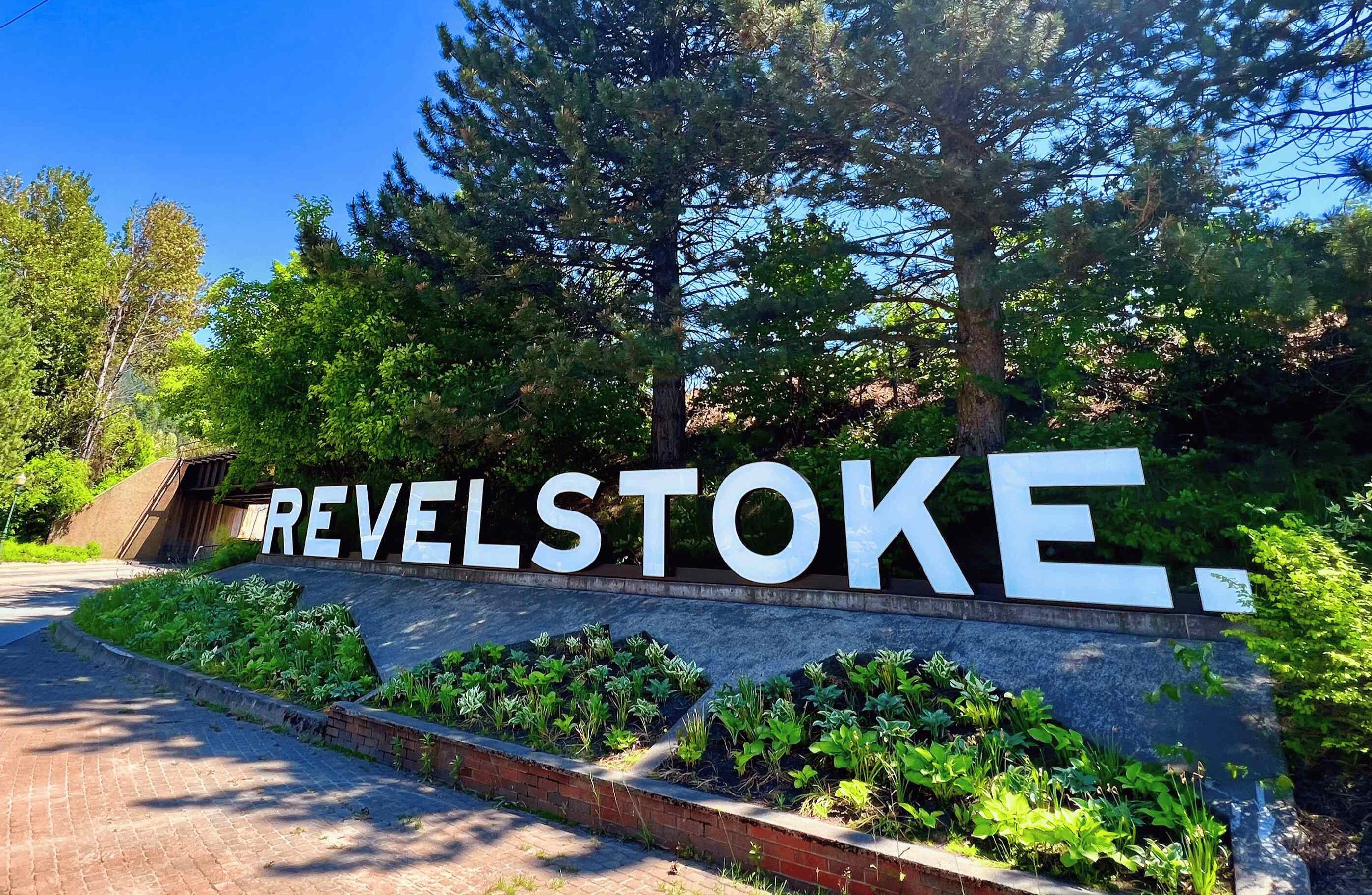 Revelstoke welcome sign surrounded by lush trees on a bright sunny day